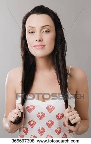 Portrait of a young woman holding her hair and smiling View Large Photo Image Stock Photo - Portrait of a young woman holding her hair and smiling. Fotosearch