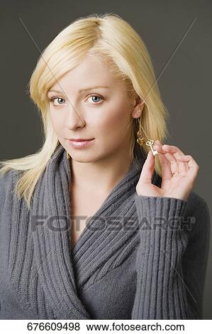 Portrait of a young woman holding her earring View Large Photo Image Stock Photo - Portrait of a young woman holding her earring. Fotosearch