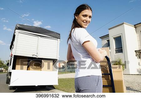 Portrait of a young woman holding cardboard boxes on a push cart View Large Photo Image Stock Image - Portrait of a young woman holding cardboard boxes on a push cart. Fotosearch