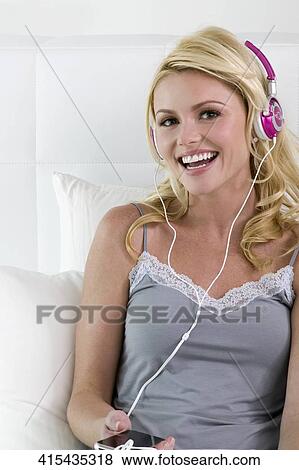 Portrait of a young woman listening to an MP3 player and smiling View Large Photo Image Stock Photo - Portrait of a young woman listening to an MP3 player and smiling. Fotosearch