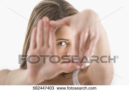 Stock Image - Portrait of a young woman looking through her hands. Fotosearch