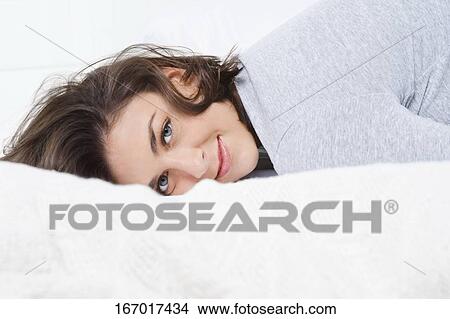 Portrait of a young woman lying on the bed and smiling View Large Photo Image Picture - Portrait of a young woman lying on the bed and smiling. Fotosearch