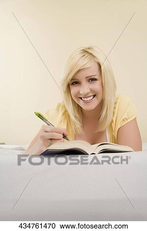 Portrait of a young woman lying on the bed and writing View Large Photo Image Stock Image - Portrait of a young woman lying on the bed and writing. Fotosearch