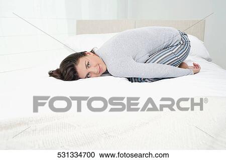 Portrait of a young woman lying on the bed and smiling View Large Photo Image Stock Image - Portrait of a young woman lying on the bed and smiling. Fotosearch