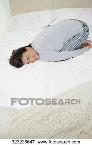 Stock Photo - Portrait of a young woman lying on the bed and smiling. Fotosearch