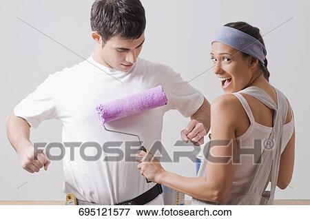 Portrait of a young woman painting on a young man's t-shirt and smiling View Large Photo Image Stock Photo - Portrait of a young woman painting on a young man's t-shirt and smiling. Fotosearch