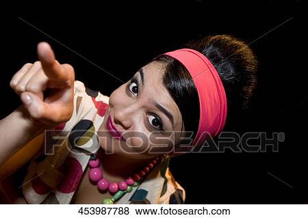 Portrait of a young woman pointing and smiling View Large Photo Image Stock Photo - Portrait of a young woman pointing and smiling. Fotosearch