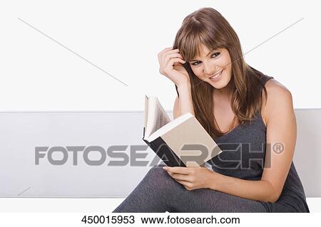 Portrait of a young woman reading a book View Large Photo Image Stock Image - Portrait of a young woman reading a book. Fotosearch