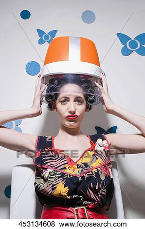 Portrait of a young woman sitting under hair dryer View Large Photo Image Stock Photo - Portrait of a young woman sitting under hair dryer. Fotosearch