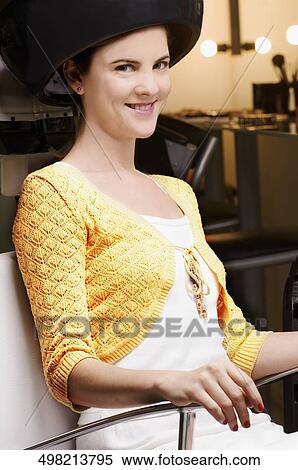 Portrait of a young woman sitting under a hair dryer View Large Photo Image Stock Photography - Portrait of a young woman sitting under a hair dryer. Fotosearch