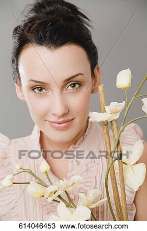 Portrait of a young woman smiling behind flowers View Large Photo Image Stock Image - Portrait of a young woman smiling behind flowers. Fotosearch
