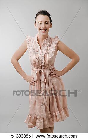 Portrait of a young woman standing with arms akimbo and smiling View Large Photo Image Stock Image - Portrait of a young woman standing with arms akimbo and smiling. Fotosearch