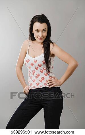Portrait of a young woman standing with arms akimbo View Large Photo Image Stock Image - Portrait of a young woman standing with arms akimbo. Fotosearch