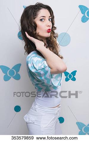 Portrait of a young woman standing with her hand in her hair View Large Photo Image Stock Photo - Portrait of a young woman standing with her hand in her hair. Fotosearch