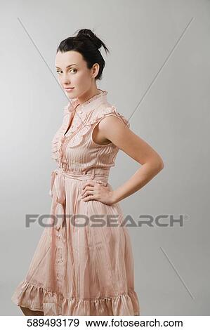 Stock Photo - Portrait of a young woman standing with her hand on her hip. Fotosearch