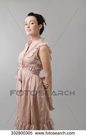 Stock Photography - Portrait of a young woman standing with her hands behind her back. Fotosearch