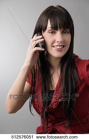 Portrait of a young woman talking on a mobile phone and smiling View Large Photo Image Stock Image - Portrait of a young woman talking on a mobile phone and smiling. Fotosearch