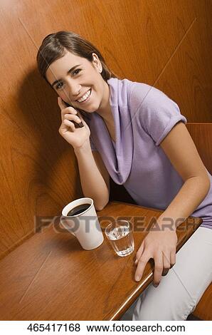 Stock Photo - Portrait of a young woman talking on a mobile phone in a cafe. Fotosearch