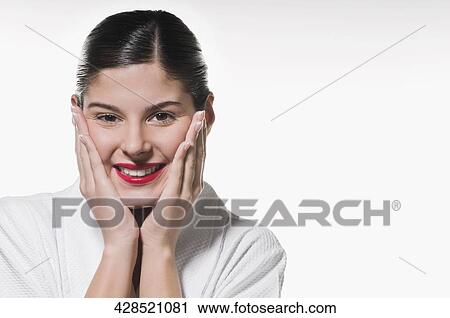Portrait of a young woman touching her cheeks and smiling View Large Photo Image Stock Image - Portrait of a young woman touching her cheeks and smiling. Fotosearch