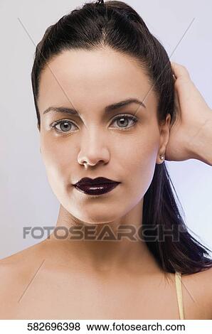 Portrait of a young woman touching her hair View Large Photo Image Stock Photo - Portrait of a young woman touching her hair. Fotosearch