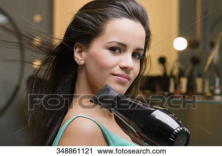 Portrait of a young woman using a hair dryer View Large Photo Image Stock Image - Portrait of a young woman using a hair dryer. Fotosearch