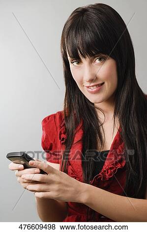 Stock Photo - Portrait of a young woman using a mobile phone and smiling. Fotosearch