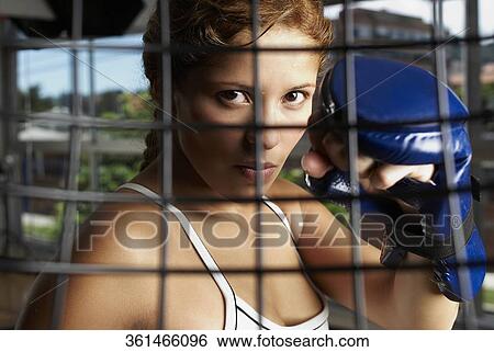Stock Photograph - Portrait of a young woman wearing a boxing glove. Fotosearch