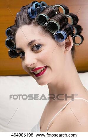 Stock Photo - Portrait of a young woman wearing hair rollers and smiling. Fotosearch