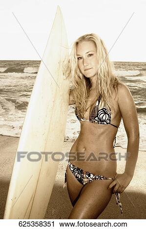 Portrait of a young woman with a surfboard standing on the beach View Large Photo Image Stock Image - Portrait of a young woman with a surfboard standing on the beach. Fotosearch