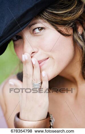 Portrait of a young woman with her hand over her mouth View Large Photo Image Stock Photo - Portrait of a young woman with her hand over her mouth. Fotosearch