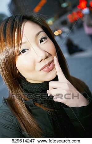 Portrait of a young woman with her finger on her lips View Large Photo Image Stock Photo - Portrait of a young woman with her finger on her lips. Fotosearch