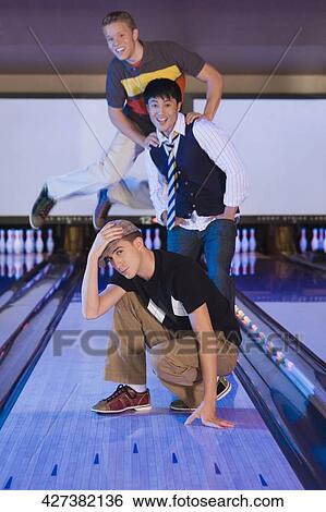 Stock Photograph - Portrait of three friends in a bowling alley. Fotosearch