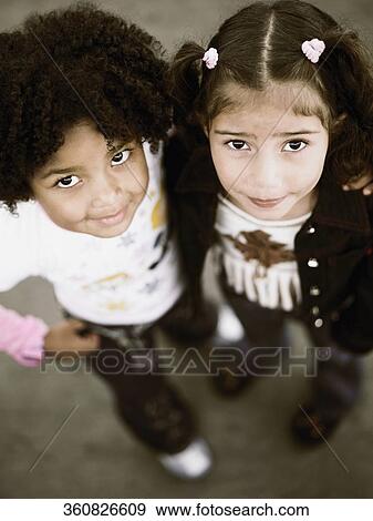 Portrait of two girls standing with their arms around each other View Large Photo Image Stock Photo - Portrait of two girls standing with their arms around each other. Fotosearch