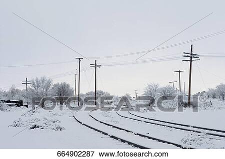 Railroad tracks passing through a snow covered landscape View Large Photo Image Stock Photo - Railroad tracks passing through a snow covered landscape. Fotosearch