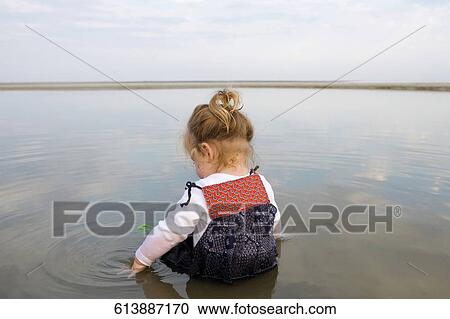 Rear view of a baby girl sitting in water View Large Photo Image Stock Image - Rear view of a baby girl sitting in water. Fotosearch