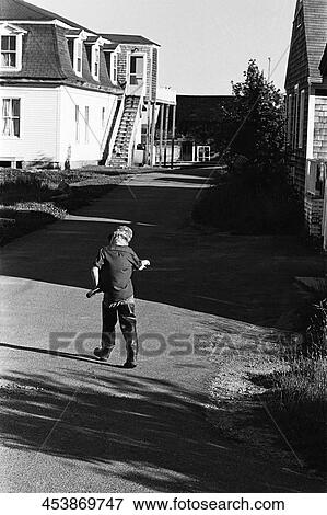 Rear view of a boy walking in the street View Large Photo Image Stock Photo - Rear view of a boy walking in the street. Fotosearch