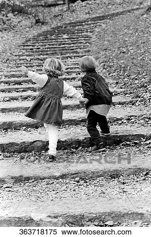 Stock Photography - Rear view of a boy with his sister moving up on steps. Fotosearch