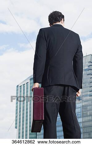 Rear view of a businessman holding a briefcase View Large Photo Image Stock Image - Rear view of a businessman holding a briefcase. Fotosearch