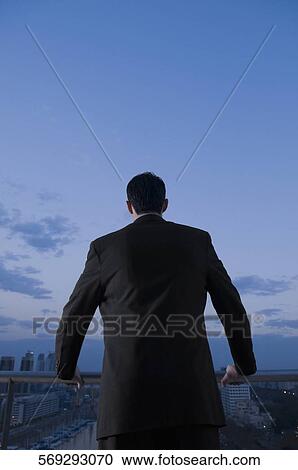 Rear view of a businessman holding a railing View Large Photo Image Stock Image - Rear view of a businessman holding a railing. Fotosearch
