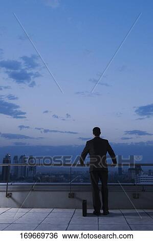 Rear view of a businessman holding a railing View Large Photo Image Stock Photograph - Rear view of a businessman holding a railing. Fotosearch