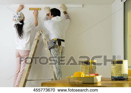 Rear view of a couple decorating the home View Large Photo Image Stock Image - Rear view of a couple decorating the home. Fotosearch