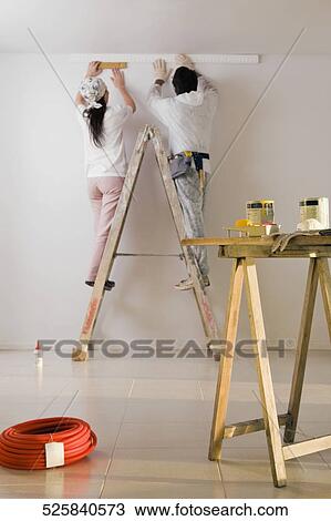 Stock Image - Rear view of a couple decorating the home. Fotosearch