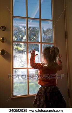 Rear view of a girl looking through a door View Large Photo Image Stock Photo - Rear view of a girl looking through a door. Fotosearch