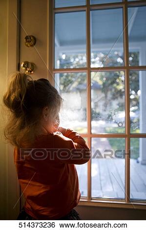 Rear view of a girl looking through a door View Large Photo Image Stock Photograph - Rear view of a girl looking through a door. Fotosearch