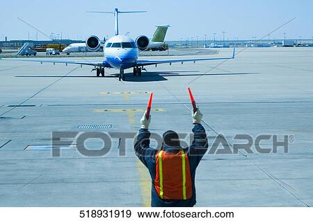 Rear view of a ground crew directing an airplane View Large Photo Image Stock Photo - Rear view of a ground crew directing an airplane. Fotosearch