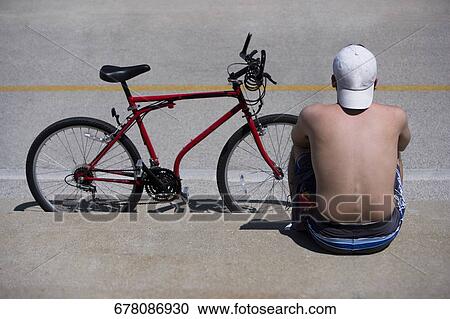 Rear view of a man sitting at roadside with a bicycle, Oak Street Beach, 1000 North Lake Shore Drive, Chicago, Illinois, USA View Large Photo Image Stock Image - Rear view of a man sitting at roadside with a bicycle, Oak Street Beach, 1000 North Lake Shore Drive, Chicago, Illinois, USA. Fotosearch