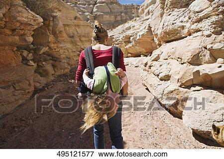 Rear view of a mid adult woman carrying her daughter in a baby carrier View Large Photo Image Stock Photo - Rear view of a mid adult woman carrying her daughter in a baby carrier. Fotosearch
