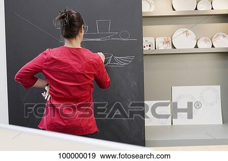 Rear view of a woman drawing on a blackboard View Large Photo Image Stock Photo - Rear view of a woman drawing on a blackboard. Fotosearch