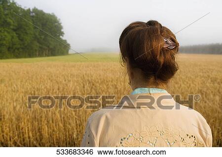 Rear view of a woman in a crop field View Large Photo Image Stock Photograph - Rear view of a woman in a crop field. Fotosearch