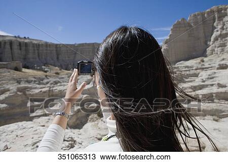 Stock Image - Rear view of a woman photographing with a digital camera. Fotosearch